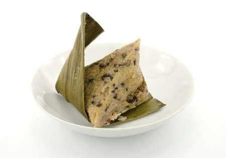 Traditional wrapped rice dumplings or zongzi on a plate, isolated on white backgroundの写真素材