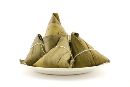 Traditional wrapped rice dumplings or zongzi on a plate, isolated on white backgroundの写真素材
