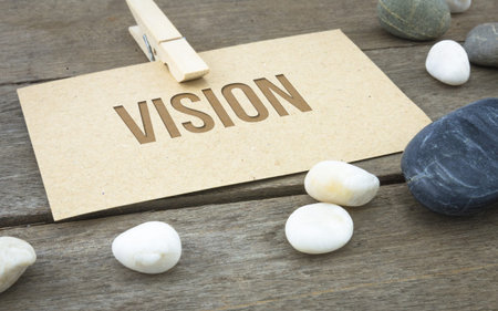 Vision, business conceptual words with brown paper sheets or notes stick on a wooden background....