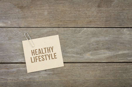 Healthy lifestyle conceptual words with brown paper sheets or notes stick on a wooden background. Attached with paper clips or pin.の写真素材