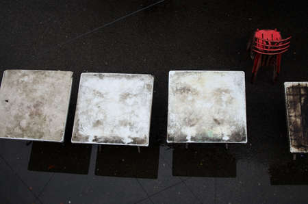 Dirty plastic white tables, red chairs & dark background, natural artistic arrangement, image taken from top.の写真素材