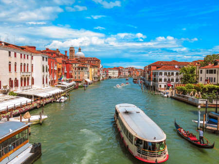 Canal in Venice with water taxi and Venetian buildings along the water on a blue summer day and clouds.のeditorial素材