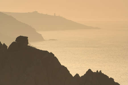 COUPLE ON CLIFF EDGE WATCHING THE SUNSETの写真素材