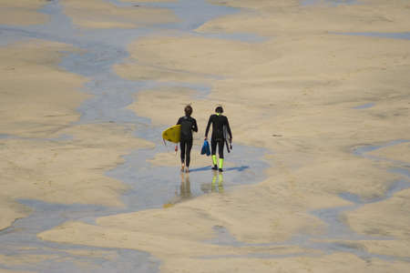 TWO SURFERS WALKING ON THE BEACH (9621)の写真素材