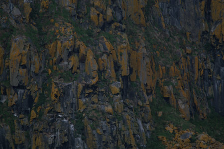 Rocky formations on the coast of Northern Ireland. Tall grassy cliffs are hit by several waves