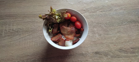 Pork fried rice in white bowl, on wooden table, top view Add red oak vegetables and small red tomatoes. Eat as an appetizer, cut greasyの写真素材