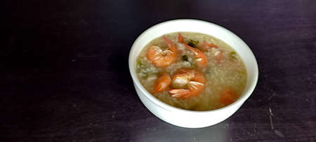 Shrimp porridge in a white bowl. Asians like to eat in the morning. It tastes delicious, smells good, is placed on a black table. from top viewの写真素材