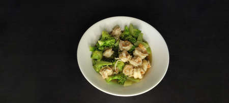 Stir fried broccoli with shrimp in white plate on black background from top viewの写真素材