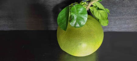 Golden Dee Grapefruit, large fruit placed on a black wooden floor: this fruit has a distinctly unique fruit appearance. is a round fruit The meat or shrimp is light pink in color. Soft, juicy fleshの写真素材