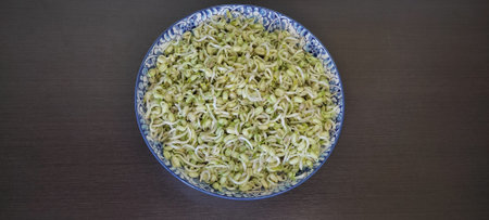The bean sprouts, naturally grown, non-toxic, ready to be cooked, are placed in a plate on a black wooden floor. from top viewの写真素材