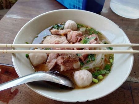 thin noodles Braised pork meatballs in a white bowl, placed on a wooden table. from top viewの写真素材