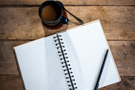 notebook pen and cup of coffee in wood tableの写真素材