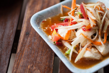 Papaya salad with the wood background. Papaya Salad is a famous Thai traditional food.の写真素材