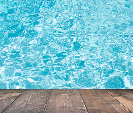 Blue swimming pool rippled water detail with wooden floorの写真素材