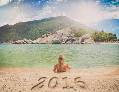 Young lady Traveler with handwriting New Year 2016 message on sand.の写真素材