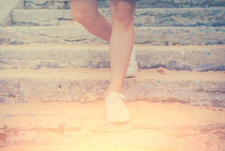 Close-up Man with sneaker shoes walking down. International sun light and vintage tone.