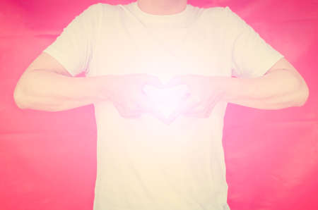 Muscle man making heart sign with pink light. Vintage tone.の写真素材