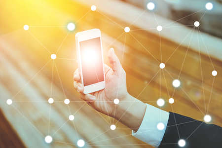 Businessman on blurred background using digital data network with mobile phoneの写真素材