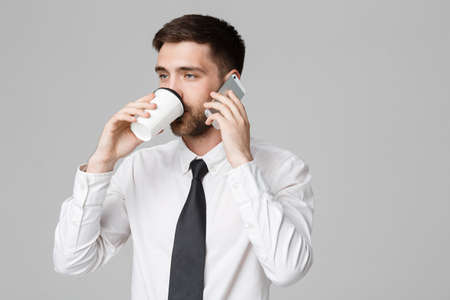 Business Concept - Portrait of a handsome businessman in eyeglasses with a cup of coffee and smartphone.の写真素材