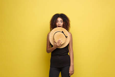 Travel concept - Close up Portrait young beautiful attractive African American woman with trendy hat smiling and joyful expression. Yellow Pastel studio Background. Copy space.の写真素材
