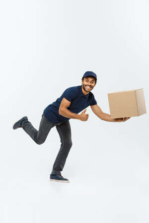 Delivery Concept - Handsome African American delivery man rush running for delivering a package for customer. Isolated on Grey studio Background. Copy Space.の写真素材