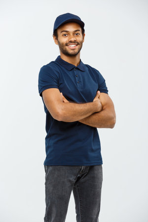 Delivery Concept - Handsome African American delivery man crossed arms over isolated on Grey studio...