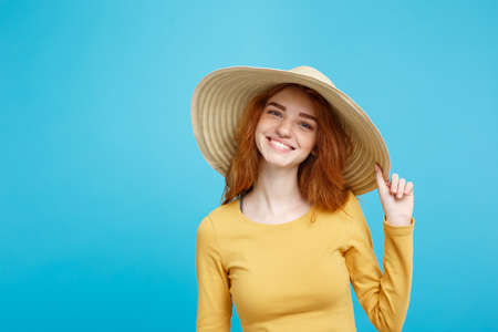 Travel concept - Close up Portrait young beautiful attractive ginger red hair girl with trendy hat and smiling. Blue Pastel Background. Copy space.の写真素材