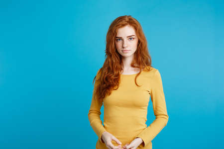 Portrait of young beautiful ginger woman confident looking at camera. Isolated on pastel blue background. Copy space.の写真素材