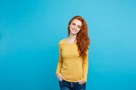 Portrait of young beautiful ginger woman with freckles cheerfuly smiling looking at camera. Isolated on pastel blue background. Copy space.の写真素材