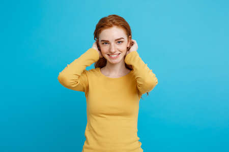 Lifestyle concept - Close up Portrait young beautiful attractive ginger red hair girl playing with her hair with shyness. Blue Pastel Background. Copy space.の写真素材