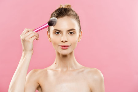Beauty Concept - Closeup Beautiful caucasian woman applying makeup with Cosmetic Powder Brush....