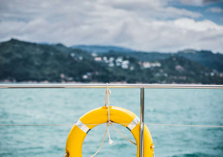 Close-up Yellow life ring hanging on boat with ocean background.の写真素材
