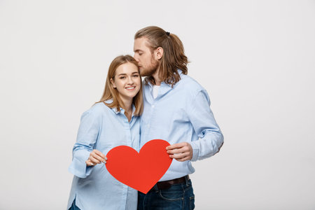 Portrait of young happy couple in love holding red paper heart.の写真素材