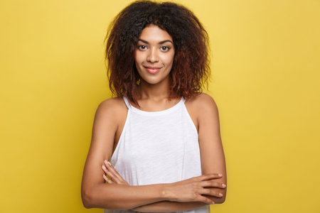 Headshot portrait of beautiful attractive African American woman posting crossed arms with happy...