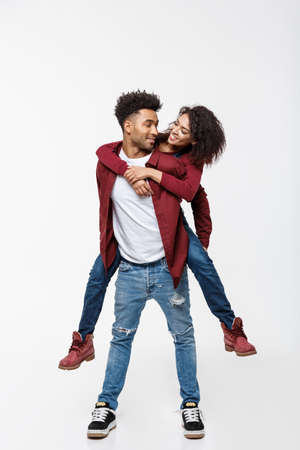 Full length young attractive african american lady riding back on her boyfriend back and enjoy playing to each other.の写真素材