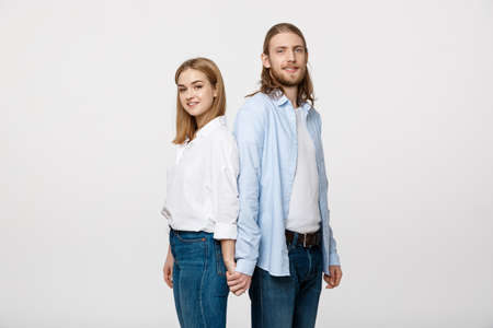 Cheerful happy man and woman with holding hands standing back to back.の写真素材
