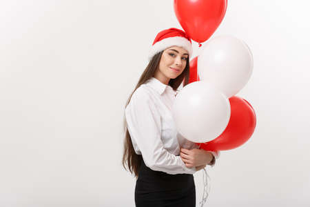 Business Concept - Beautiful young confident business woman with santa hat holding balloon celebrate for Christmas.の写真素材