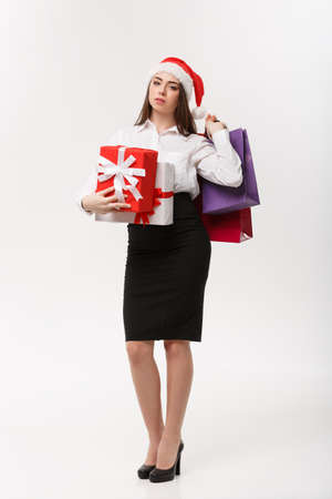 Christmas Concept - beautiful business woman holding shopping bags and present with exhausted feeling.の写真素材