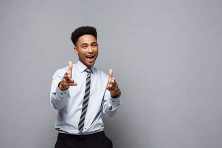 Business Concept - Cheerful happy young African American holding gun sign with fingers pointing to...