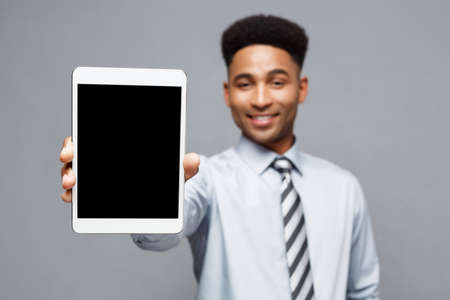 Business Concept - Happy handsome professional african american businessman showing digital tablet to client.の写真素材