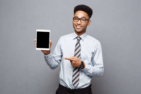 Business Concept - Happy handsome professional african american businessman showing digital tablet to client.の写真素材