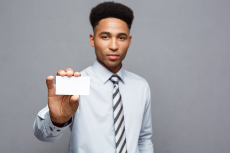 Business Concept - Happy handsome professional african american businessman showing name card to client.の写真素材