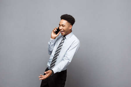 Business Concept - Cheerful professional african american businessman happy talking on mobile phone with client.の写真素材