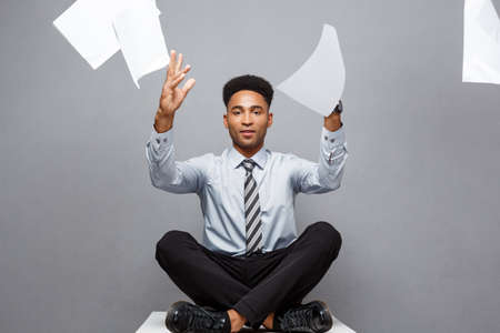 Business Concept - handsome young professional african american businessman throwing away pile of paperworks flying on air.の写真素材