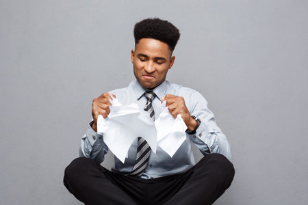 Business Concept - handsome young professional african american businessman throwing away pile of...