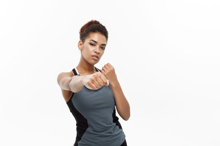 Healthy and Fitness concept - portrait of African American woman punching in air with confident...