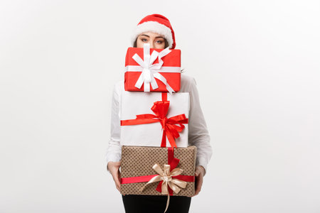 Business Concept - Beautiful young caucasian business woman with santa hat hiding behide a lot of...