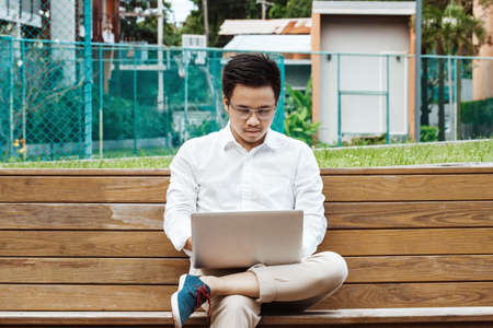 Young businessman working on laptop at gardenの写真素材
