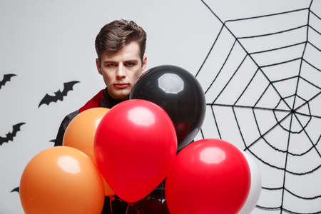 Portrait of handsome caucasian in Vampire halloween costume with colorful Balloon.の写真素材
