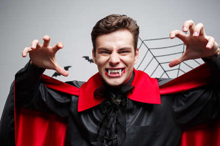 Vampire Halloween Concept - Portrait of handsome caucasian Vampire halloween costume fluttering his red, black cloak.の写真素材